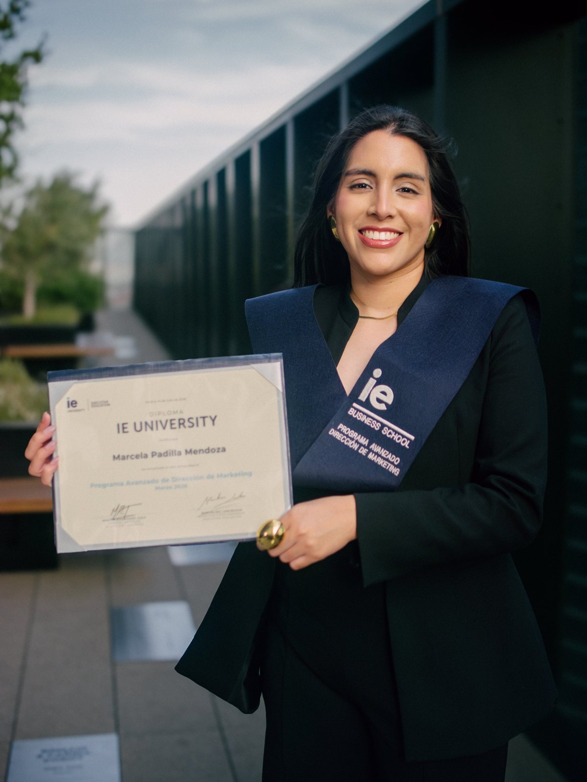 Marcela holding her IE Business School diploma